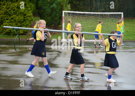 Schülerinnen und Schüler tragen ein Korbball-Ziel in unserer lieben Frau & St. Werburgh's katholische Grundschule in Newcastle-under-Lyme, Staffordshi Stockfoto