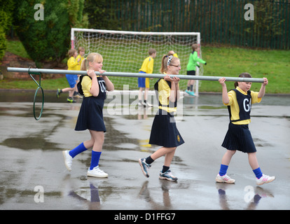 Schülerinnen und Schüler tragen ein Korbball-Ziel in unserer lieben Frau & St. Werburgh's katholische Grundschule in Newcastle-under-Lyme, Staffordshi Stockfoto