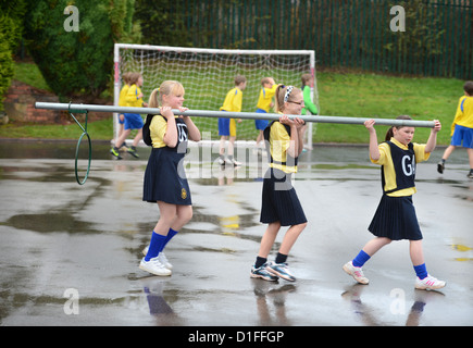 Schülerinnen und Schüler tragen ein Korbball-Ziel in unserer lieben Frau & St. Werburgh's katholische Grundschule in Newcastle-under-Lyme, Staffordshi Stockfoto