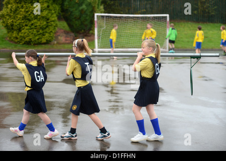 Schülerinnen und Schüler tragen ein Korbball-Ziel in unserer lieben Frau & St. Werburgh's katholische Grundschule in Newcastle-under-Lyme, Staffordshi Stockfoto