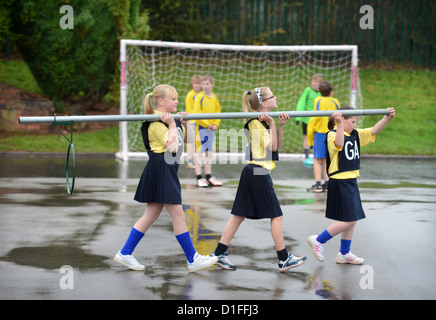 Schülerinnen und Schüler tragen ein Korbball-Ziel in unserer lieben Frau & St. Werburgh's katholische Grundschule in Newcastle-under-Lyme, Staffordshi Stockfoto