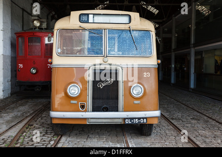 Vor dem alten braunen und weißen Bus und roter Trolley auf der Kopfsteinpflasterstraße in der Durchgangsgarage. Stockfoto