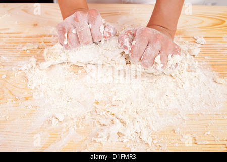 Hände, Teig auf dem Holzbrett Stockfoto