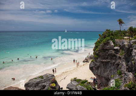 Menschen schwimmen am wunderschönen Strand unterhalb der spektakuläre Maya-Ruinen in Tulum. Stockfoto