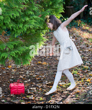 9 Jahre altes Mädchen für Anlass mit einem Geschenk unter einem Baum im freien gekleidet. Weihnachts-Szene. Stockfoto