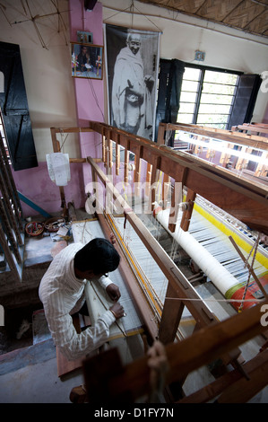 Mann arbeitet einen Webstuhl in einem Dorf weben Workshop unter ein großes Bild von Mahatma Gandhi, Kalna, West Bengalen, Indien, Asien Stockfoto