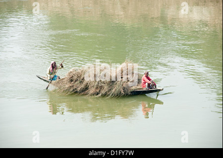 Schiffer paddeln hölzerne Boot beladen mit Stroh über den Fluss Hugli (Hooghly River), ländlichen West Bengalen, Indien, Asien Stockfoto