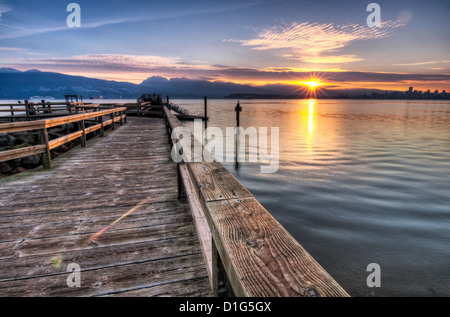 Pier, die ausziehen, das Wasser, während Sonne Stern über die Berge und die Skyline von Vancouver steigt ist auf der rechten Seite des Fotos ersichtlich. Stockfoto