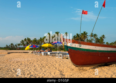 Traditionellen Fischerboot und Sonnenanbeter am Strand, Benaulim, Goa, Indien, Asien Stockfoto