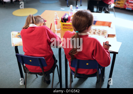 Zwei Grundschule Mädchen saß am Schreibtisch Tisch arbeiten, Rückansicht, Grundschule, UK Stockfoto