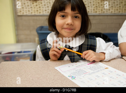 Lächelndes Hispanic zweite Klasse Grundschule Mädchen in Uniform im Klassenzimmer an privaten katholischen Schule in Texas Stockfoto