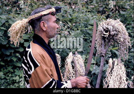 Ein bärtiger Ainu-Mann im traditionellen Kleid führt 1962 auf der Insel Hokkaido in Japan eine Friedhofszeremonie vor einem Bärenschädel auf einem Pfosten durch. Stockfoto