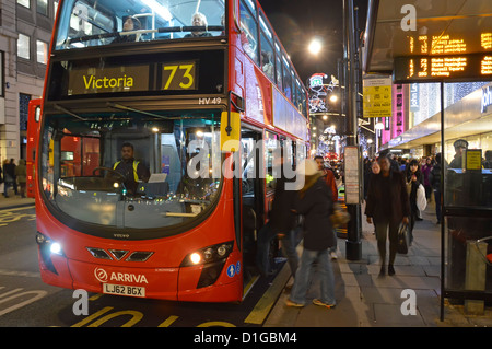 Bushaltestelle Shelter Nachtfahrplananzeige Leute steigen in den roten Arriva Doppeldecker Route 73 Bus & Fahrer Oxford Street West End London England Großbritannien Stockfoto