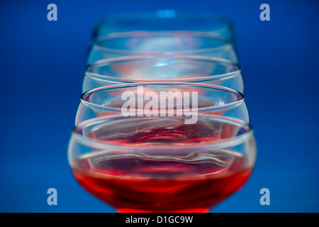 Gruppe von Gläsern gefüllt mit Rotwein auf blauem Hintergrund. Stockfoto