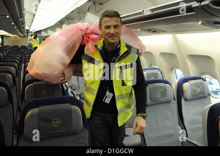 Ein Asssistant entfernt Zeitschriften aus einem Airbus a-340-Flugzeuge am Flughafen in Frankfurt Am Main, Deutschland, 18. Dezember 2012. Jedes Stück was entbehrlich war hatte gewogen und entfernt aus dem Flugzeug um herauszufinden, wie viel Gewicht eingespart werden könnten. Foto: BORIS ROESSLER Stockfoto