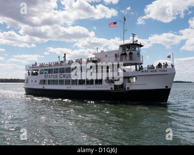 Eine Statue Cruises Touristenboot verlässt das Dock im Hafen von New York City unter einer anderen Gruppe von Besuchern, um zu sehen, die Statue des Stockfoto