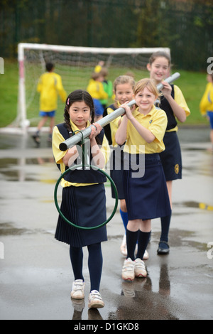 Schülerinnen und Schüler tragen ein Korbball-Ziel in unserer lieben Frau & St. Werburgh's katholische Grundschule in Newcastle-under-Lyme, Staffordshi Stockfoto