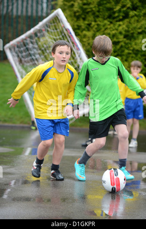 Schule Jungs dribbling ein Fußballspiel am Ende eine regnete Praxis entsprechen in katholischen Grundschule Muttergottes & St. Werburgh's Stockfoto