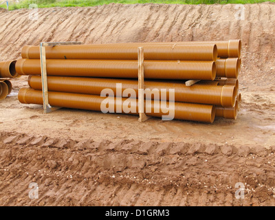 Stapel von neuen braune Wellpappe Twin Wand UPVC Oberflächenwasser Abflussrohre auf einer Straßenbaustelle UK Stockfoto