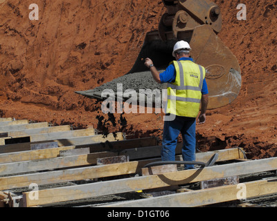 Gießen von Beton aus einem Bagger Eimer für eine Stahlbeton-Brücke Stiftung Streifen Fundament UK Stockfoto