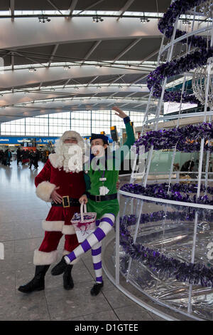 21. Dezember 2012.  T5 Flughafen Heathrow, London. Akteure in Santa verkleidet und Elf Kostüme, Reisende, was erwartet wurde, zu den verkehrsreichsten Tag für Weihnachten zu unterhalten Reisen. © Danny Callcut Stockfoto