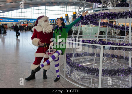 21. Dezember 2012.  T5 Flughafen Heathrow, London. Akteure in Santa verkleidet und Elf Kostüme, Reisende, was erwartet wurde, zu den verkehrsreichsten Tag für Weihnachten zu unterhalten Reisen. © Danny Callcut Stockfoto