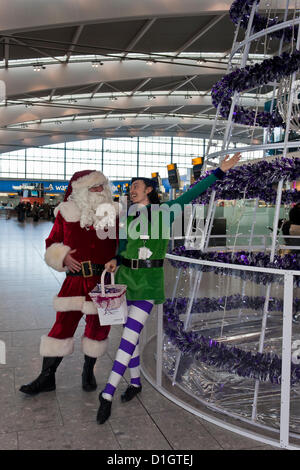 21. Dezember 2012.  T5 Flughafen Heathrow, London. Akteure in Santa verkleidet und Elf Kostüme, Reisende, was erwartet wurde, zu den verkehrsreichsten Tag für Weihnachten zu unterhalten Reisen. © Danny Callcut Stockfoto