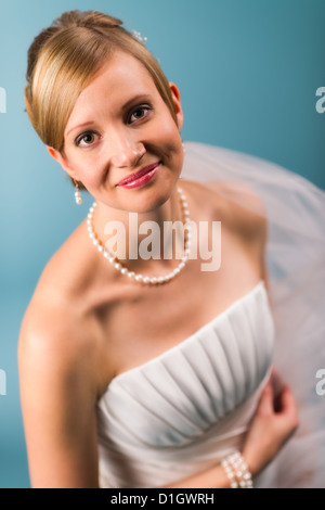 Schöne Braut trägt weiße Hochzeitskleid, blauer Hintergrund Stockfoto