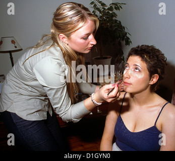 Frau Auftragen von Lippenstift auf Braut vor der Hochzeit Stockfoto