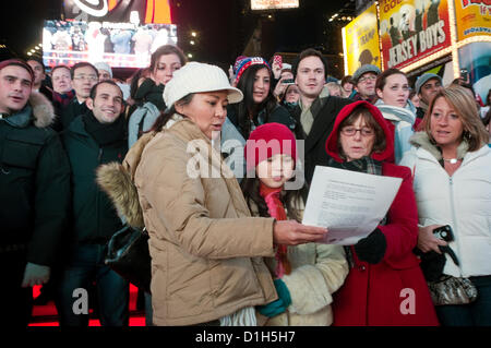 New York, NY - 21 Dezember 2012 über 500 Menschen erfüllt die rote Schritte auf dem Times Square willkommen Yoko Ono, Witwe des verstorbenen John Lennon, um Frieden von Lied Lennons "Imagine" mehrere hundert mehr versammelten sich in der Mall der Duffy Square zum Mitsingen zu feiern.  Zeitgleich mit der Wintersonnenwende zusammen, war das Lied Führung durch Thomas McCarger, Dirigent und Sänger, und unter der Schirmherrschaft von Make Music New York. Stockfoto