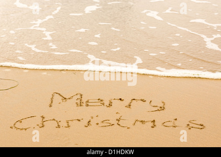 Frohe Weihnachten-Zeichen im Sand am Strand geschrieben Stockfoto