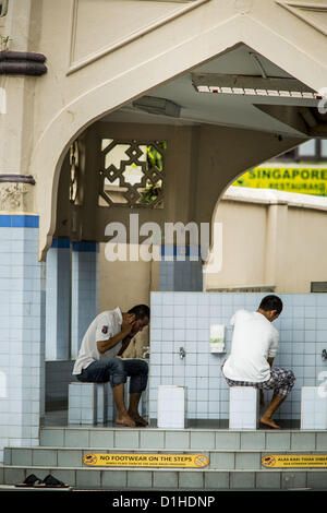 22. Dezember 2012 - Singapur, Singapur - Männer führen Waschungen, die rituelle Waschung und Reinigung Muslime tun vor dem Betreten einer Moschee zum Gebet in der Sultan-Moschee in Singapur. Die Sultansmoschee steht im Mittelpunkt des historischen Kampong Glam-Bereichs von Singapur. Auch bekannt als Masjid Sultan, hieß es für Sultan Hussein Shah. Die Moschee wurde ursprünglich in den 1820er Jahren gebaut. Die ursprüngliche Struktur wurde 1924 das heutige Gebäude weichen die 1928 fertiggestellt wurde abgerissen. Die Moschee hat großen Bedeutung für die muslimische Gemeinschaft und gilt als die Nationalmoschee Singapo Stockfoto