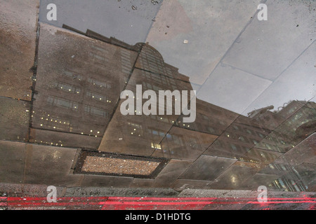 Reflexion des Gebäudes in Pflaster Pfütze an einem regnerischen Tag in der City of London Stockfoto