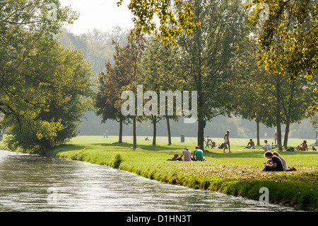 Menschen entspannen neben Eisbach in Englischer Garten, München, Bavarie, Deutschland Stockfoto