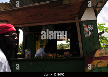 African-West Indian Mann mit roter Mütze, vorbei an Grün lackierten hölzernen Kiosk mit Gemüse, Grenville, Grenada, West Indies Stockfoto