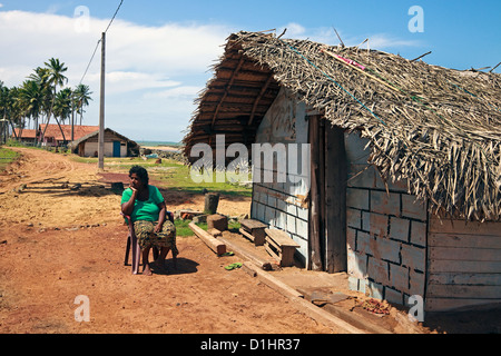 Frau sitzt auf einem Kunststoff-Sitz, vor ihrem Haus in Waikkal Dorf, Sri Lanka Stockfoto