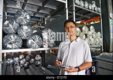 Ein Manager mit einem Klemmbrett steht neben einer Palette der Walze Stoff Stockfoto