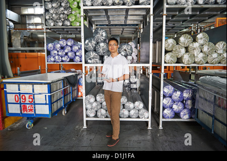 Ein Manager mit einem Klemmbrett steht neben einer Palette der Walze Stoff Stockfoto
