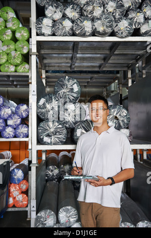 Ein Manager mit einem Klemmbrett steht neben einer Palette der Walze Stoff Stockfoto