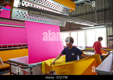 Arbeitnehmer ziehen und prüfen neu gepressten rosa Stoff in Behältern Stockfoto