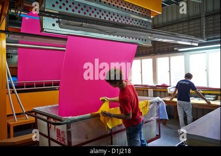 Arbeitnehmer ziehen und prüfen neu gepressten rosa Stoff in Behältern Stockfoto