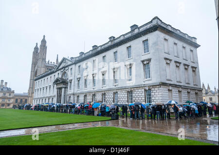 Kings College Cambridge UK 24. Dezember 2012. Massen-Warteschlange im strömenden Regen für Tickets für das Festival of Nine Lessons and Carols statt in der berühmten Kapelle am Heiligabend. Manche Menschen lagerten über Nacht und andere kamen um 04:30 um einen Platz in der Warteschlange zu sichern.  Das Konzert ist auf der ganzen Welt übertragen. Das Wetter dämpfen der Menschen Geister nicht. Stockfoto