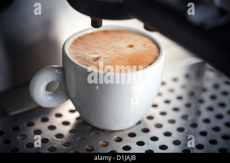 Weiße Keramik Tasse frischen Espresso mit Schaum in der Kaffeemaschine. Stockfoto