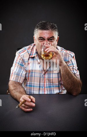 Porträt eines Mannes Reifen Mafia, trinken und Rauchen beim Sitzen am Tisch auf grauem Hintergrund Stockfoto