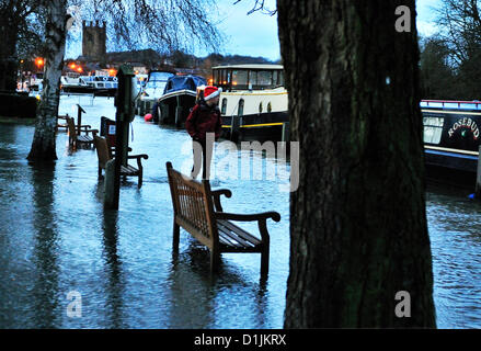 Henley Buckinghamshire UK 17.00 Uhr GMT 20.12.2012 A Santa Zecher nicht vereitelt durch die steigenden Fluten und findet ein traditionelles Weihnachten gehen (wade0 entlang der Themse Seite Treidelpfad am Mühle Wiesen, Henley-on-Thames, gesehen mit Heiliges Marys Kirche Henley hinter Stockfoto