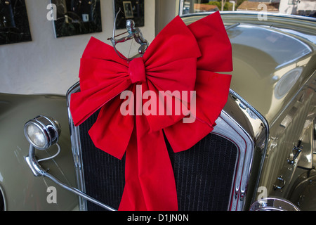 Die Kühlerfigur und eine rote Schleife für Weihnachten auf der Vorderseite eines 1929 Pierce Arrow-Cabrio-Coupés. Stockfoto