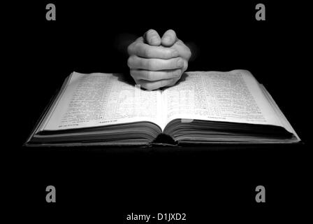 A mans Hände im Gebet über eine Bibel Stockfoto
