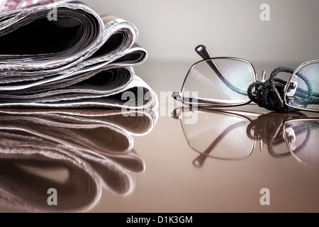 Haufen von Zeitung & Gläser auf Tisch Stockfoto