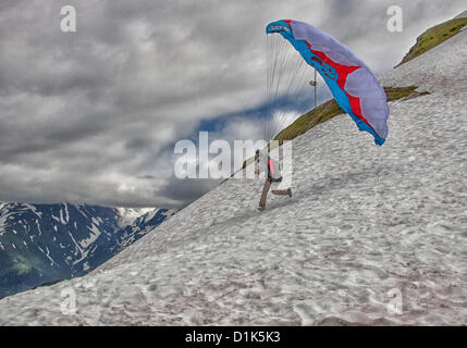 30. Juni 2012 - Girdwood, Alaska, USA - 3 in einer Reihe. Ein Gleitschirm beginnt seinen Lauf, von 2300 Fuß über dem Meeresspiegel an der Nordwand des Mt Alyeska zu starten. Er wird in einem Kabelbaum ausgesetzt unter der bunten Stoff Flügel sitzen. Reservieren Sie Fallschirme, Helm, Stiefeln und Flug-Anzüge sind erforderlich. Mt. Alyeska, der größten Skiberg im Zustand, liegt in Girdwood, Alaska, 27 Meilen (44Â km) von Anchorage, ein Lieblings Startplatz für Gleitschirmflieger. (Kredit-Bild: © Arnold Drapkin/ZUMAPRESS.com) Stockfoto