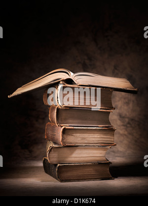 Alte Bücher gestapelt, mit einem offenen Buch an der Spitze. Stockfoto